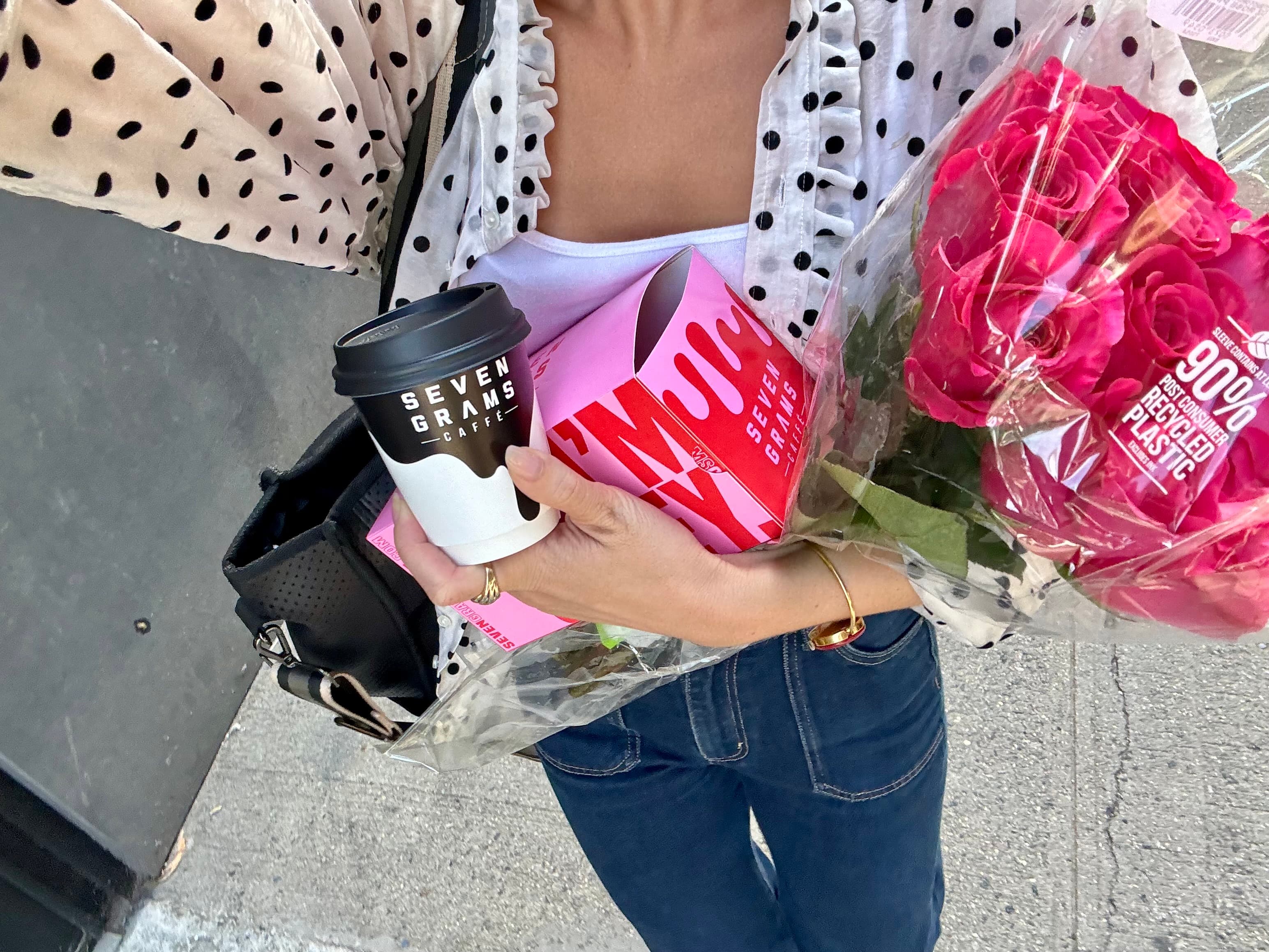 A host carrying coffee, a gift box, and fresh roses